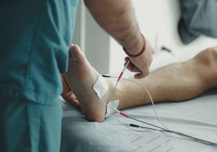 Es veu el peu d'una persona en una llitera i un professional sanitari col·locant-li uns cables